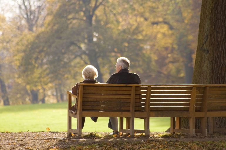 Picturesque couple sitting on a park bench in the middle of fall | Thanksgiving.com