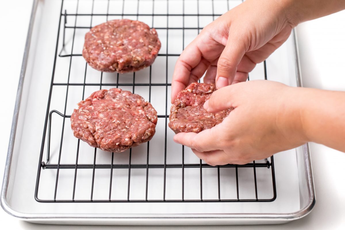 Oven baked burgers placing raw burger patties on oven rack