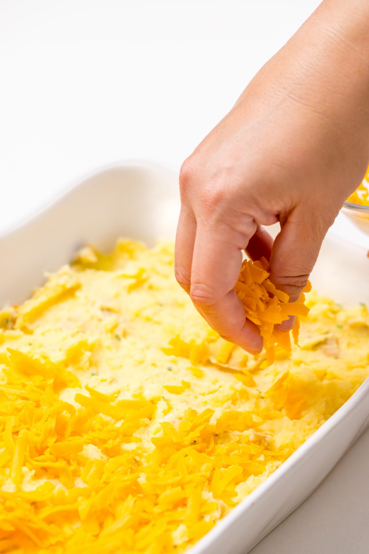 After placing one half of the mashed potatoes into the dish, top with cheddar cheese.