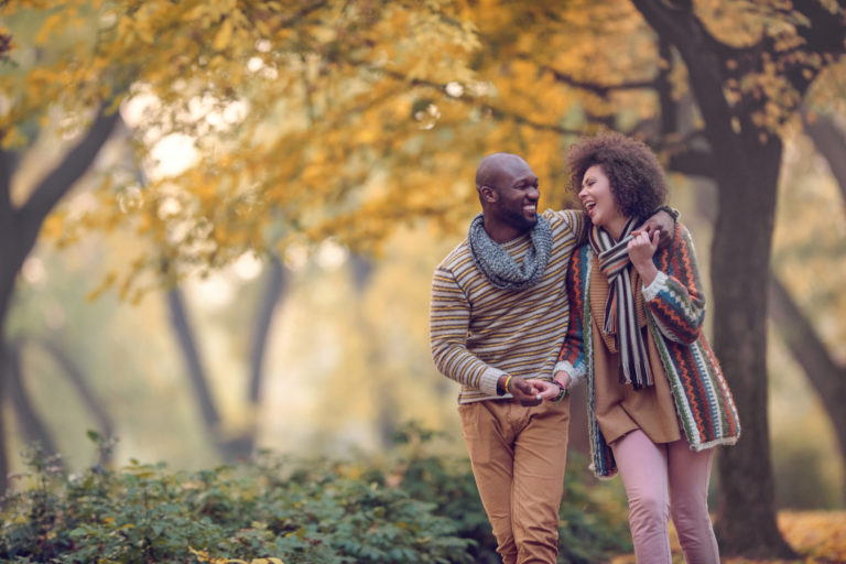 Happy African American couple walking in autumn park and laughing.