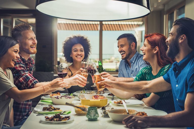Group of happy friends toasting while eating at dining table.