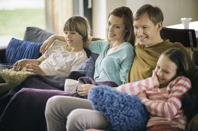 Family relaxing on sofa watching television